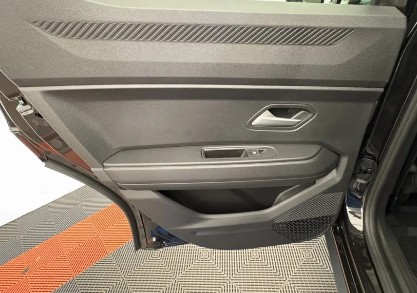 Gros plan sur la porte arrière droite noire du Dacia Duster 2025, montrant la poignée et les commandes de vitre.