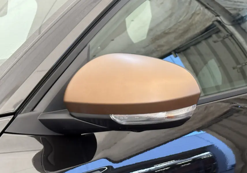 Gros plan sur le rétroviseur côté gauche du Dacia Duster 2025 noir avec clignotant intégré et coque marron.