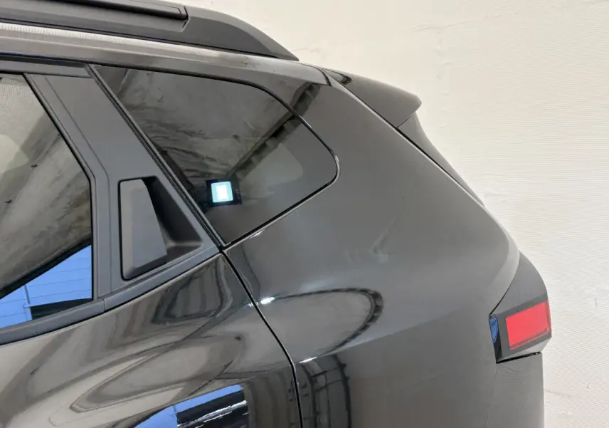 Dacia Duster noir vu de l'arrière côté gauche, mettant en valeur la lunette arrière et le feu arrière rectangulaire.