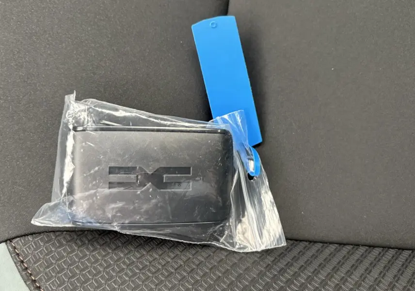 Clé noire Dacia Extreme Mild Hybrid posée sur un siège tissu noir avec surpiqûres marron, vue rapprochée intérieure.