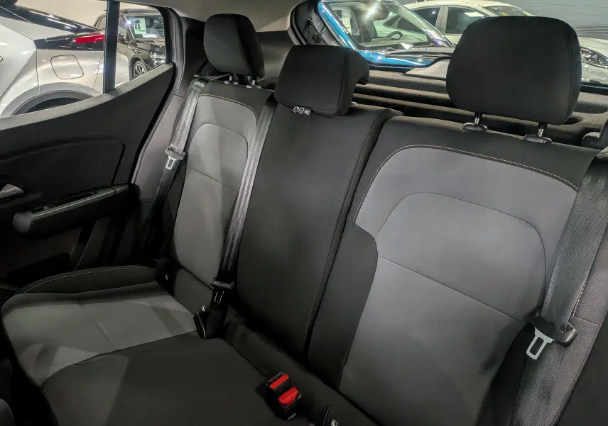 Vue intérieure des sièges arrière en tissu noir et gris du Dacia Sandero Stepway TCe 110 Gris Schiste, avec ceintures de sécurité visibles.