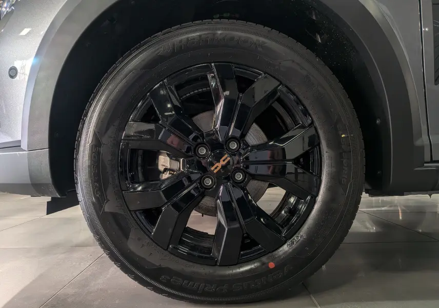 Gros plan sur la roue avant droite noire brillante d'une Dacia Sandero Stepway Gris Schiste 2025.