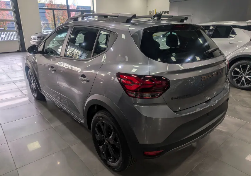 Vue 3/4 avant gauche d'une Dacia Sandero Stepway TCe 110 gris schiste en showroom avec jantes alliage noires.