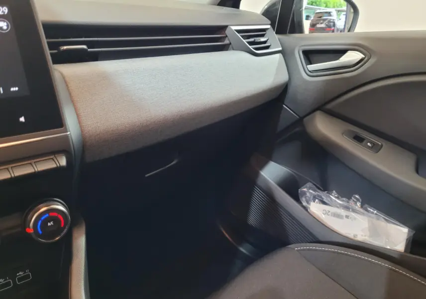 Intérieur côté passager de la Renault Clio gris foncé 2025, avec tableau de bord texturé et commandes climatisation visibles.