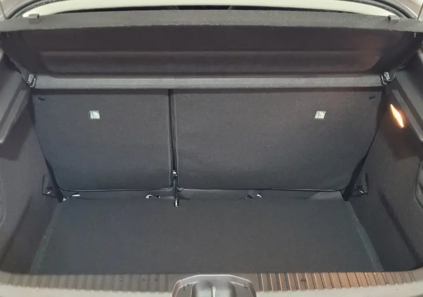 Coffre ouvert vu de l'arrière d'une Renault Clio gris foncé, montrant la banquette arrière et l'espace de chargement.