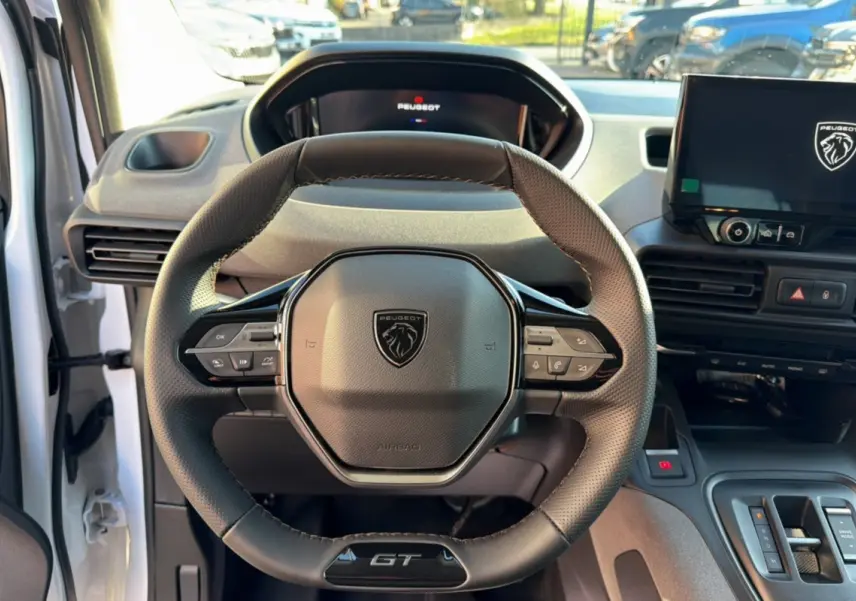 Vue intérieure centrée sur le volant cuir multifonctions du Peugeot Rifter GT Plus avec tableau de bord et écran tactile.