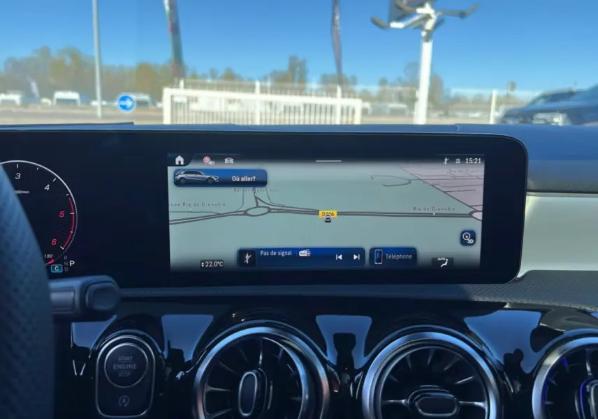 Vue intérieure du tableau de bord de la Mercedes Classe A 200D avec écran GPS large et aérateurs ronds noirs brillants.