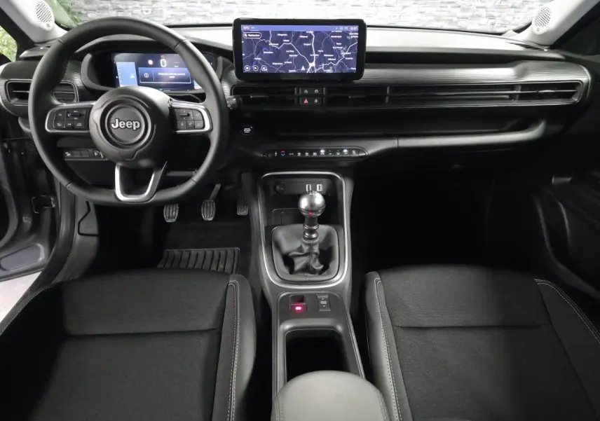 Vue intérieure avant du Jeep Avenger 2025, montrant le volant, la boîte manuelle et l'écran tactile central.