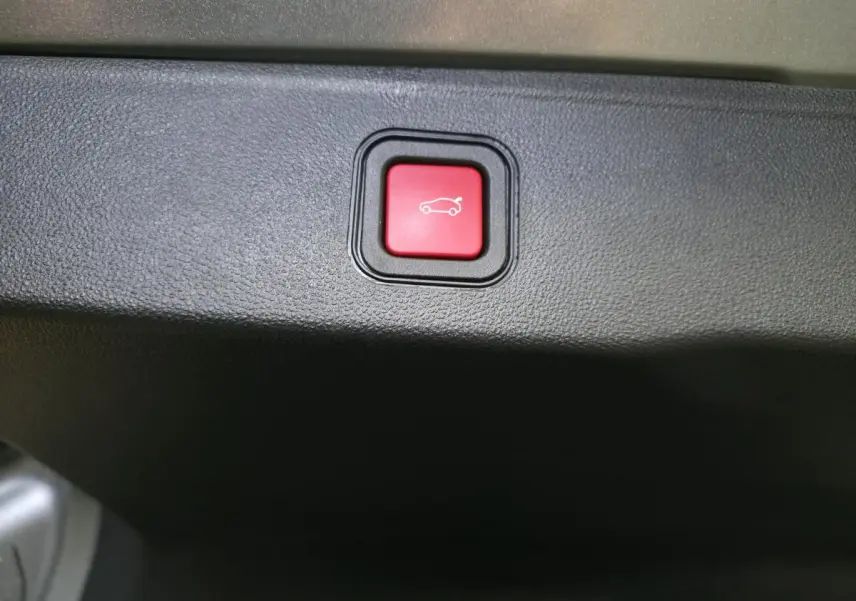 Bouton rouge d'ouverture électrique du hayon sur la garniture intérieure du coffre du Jeep Avenger gris 2025.