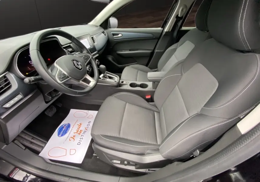 Vue intérieure côté conducteur de la Renault Arkana 2024, sièges gris et volant multifonctions noir avec logo Renault.