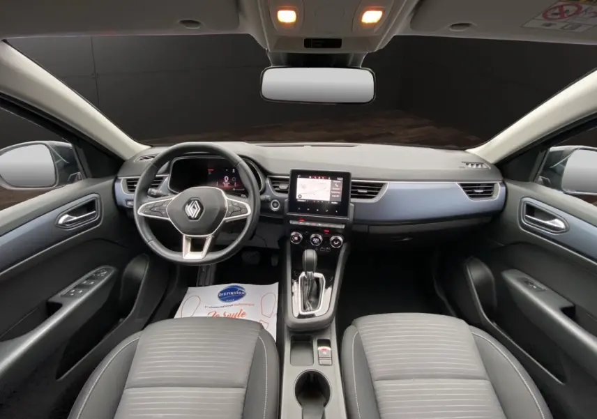 Vue intérieure avant du Renault Arkana 2024 noir, tableau de bord moderne avec écran tactile central et volant multifonctions.