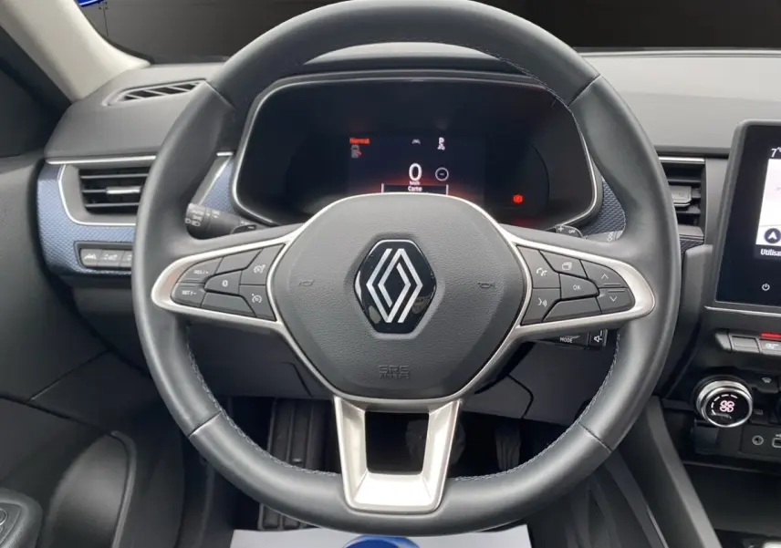 Vue rapprochée du volant cuir noir et alu du Renault Arkana 2024 avec tableau de bord numérique et écran tactile central.