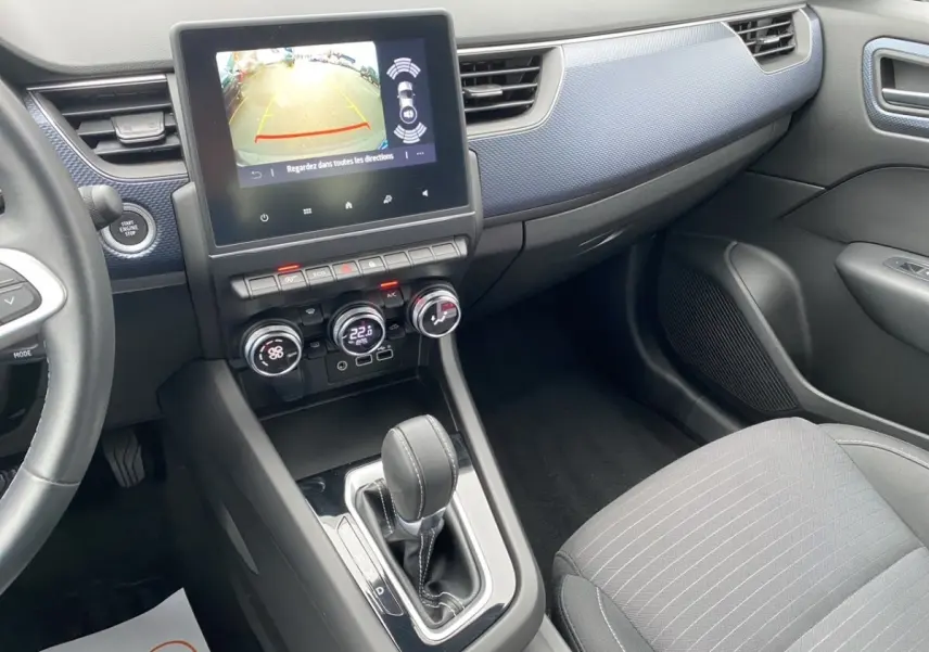 Vue intérieure côté passager du tableau de bord et console centrale noire du Renault Arkana 2024 avec écran tactile et levier de boîte auto.