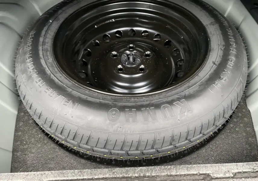 Gros plan sur la roue de secours noire en acier dans le coffre du Renault Arkana 2024 noir.