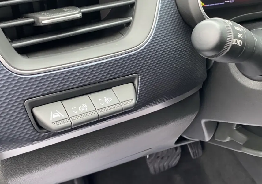 Détail des commandes d'assistance et réglages des phares sur le tableau de bord noir du Renault Arkana 2024.
