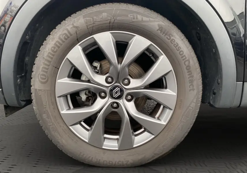 Gros plan sur la roue avant droite du Renault Arkana noir, avec jante alliage et pneu Continental AllSeasonContact.