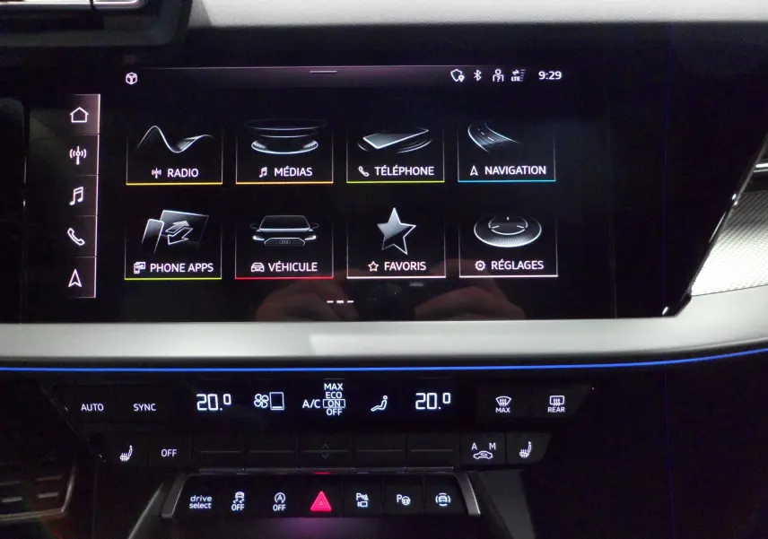 Écran tactile central de l'Audi A3 Sportback 2025 affichant les menus radio, médias, téléphone et navigation, ambiance lumineuse bleue.