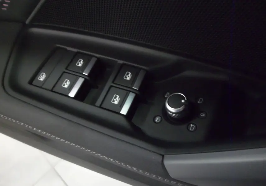 Gros plan sur les commandes des vitres et rétroviseurs côté conducteur de l'Audi A3 Sportback noir Mythe 2025.