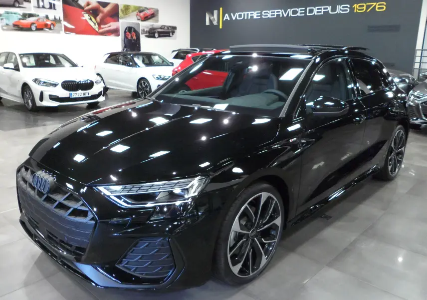 Audi A3 Sportback noir mythe vue 3/4 avant droit en showroom, avec jantes biton et calandre S-Line distinctive.