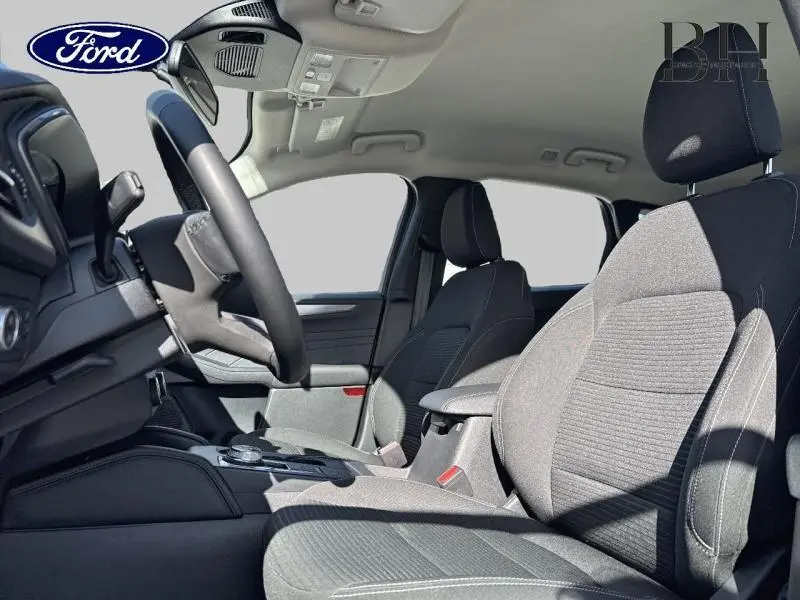 Intérieur du Ford Kuga 2023 vu côté gauche, sièges sport gris avec volant cuir multifonction visible.