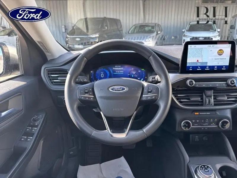Vue intérieure centrée sur le volant cuir multifonction et l'écran tactile du Ford Kuga 2023 gris Solar Métallisée.
