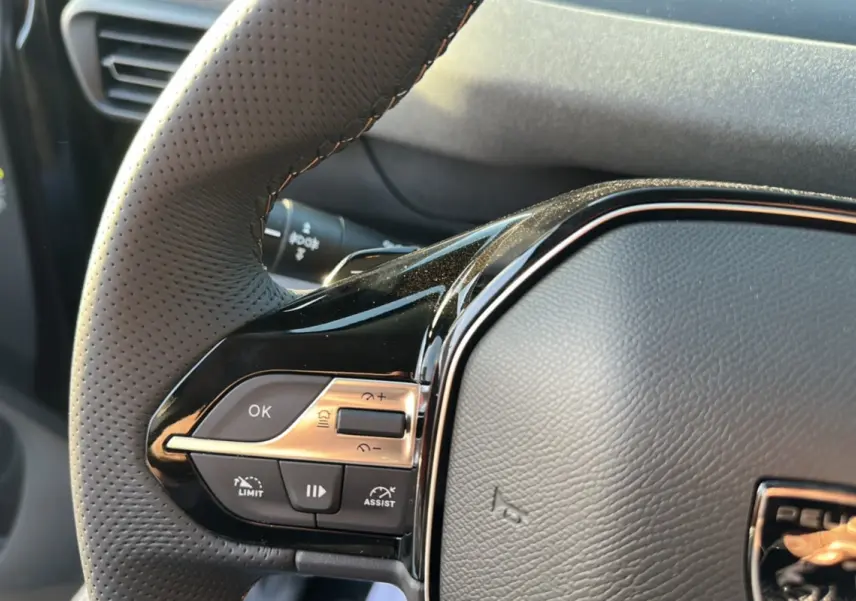 Gros plan sur le volant cuir perforé du Peugeot Rifter noir perla nera, avec commandes multifonctions visibles à gauche.