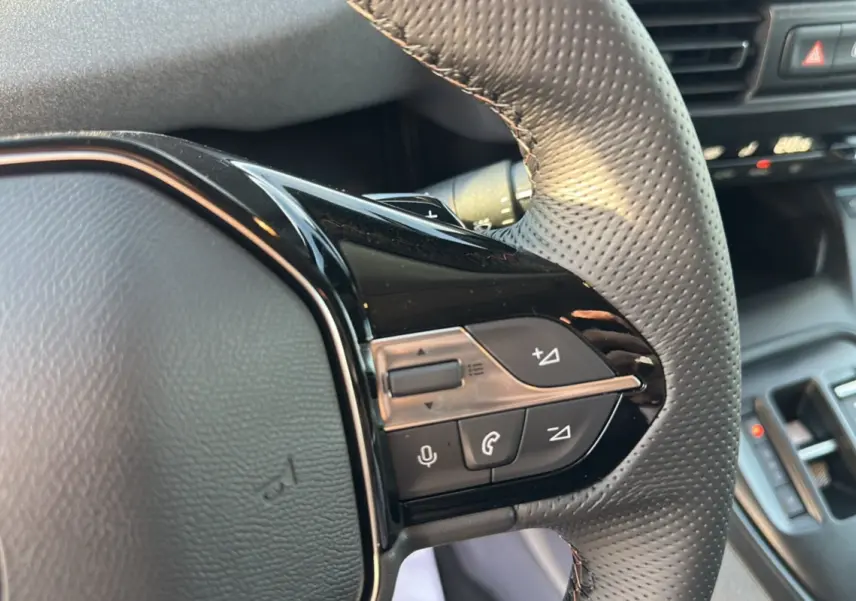 Gros plan sur les commandes multifonctions du volant cuir perforé du Peugeot Rifter noir perla nera, version 2025.