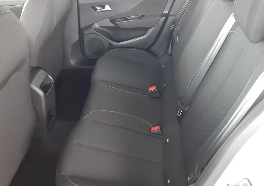 Intérieur arrière de la Peugeot 308 blanc banquise, vue côté droit montrant les sièges noirs en tissu et la porte ouverte.