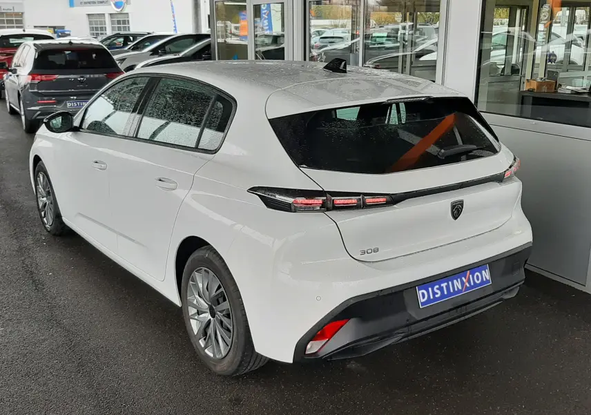 Peugeot 308 blanc banquise vue 3/4 arrière droit, feux arrière LED et toit avec antenne requin sous abri.