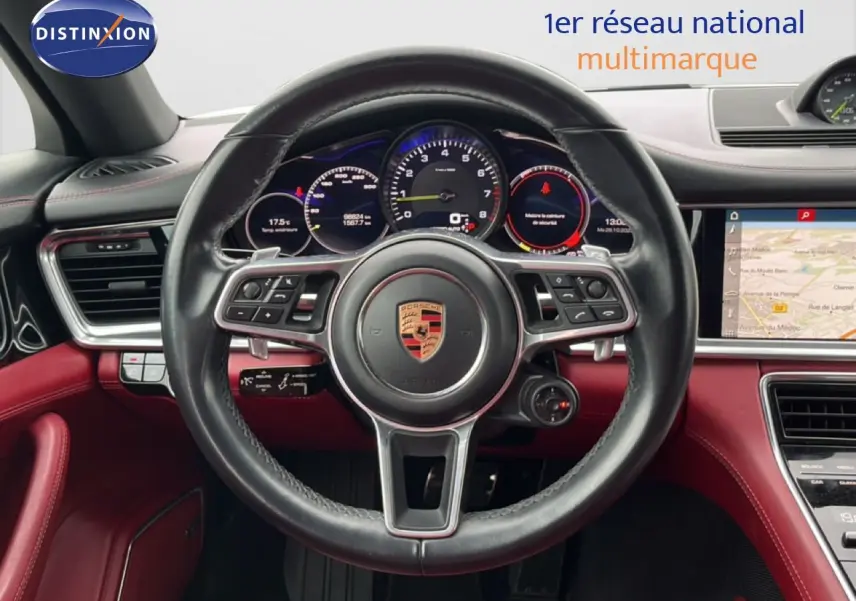 Vue centrée sur le volant cuir noir et tableau de bord rouge du Porsche Panamera 4 E-Hybrid avec affichages numériques.