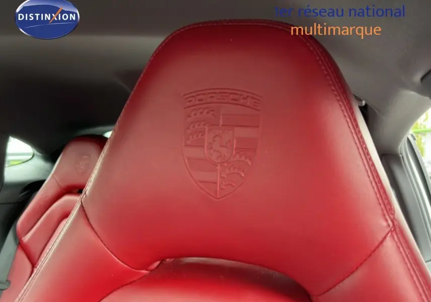 Gros plan sur l'appui-tête en cuir rouge embossé du logo Porsche à l'intérieur d'une Panamera 4 E-Hybrid blanche.