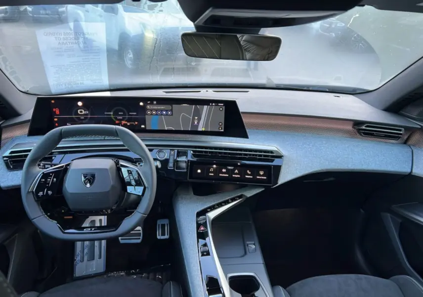 Vue intérieure frontale du Peugeot 3008 Hybrid GT 2025 avec tableau de bord numérique et volant cuir multifonctions.