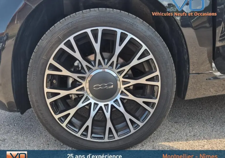 Gros plan sur la roue avant gauche noire avec jante multibranches du FIAT 500C 1.0 hybride 2024.