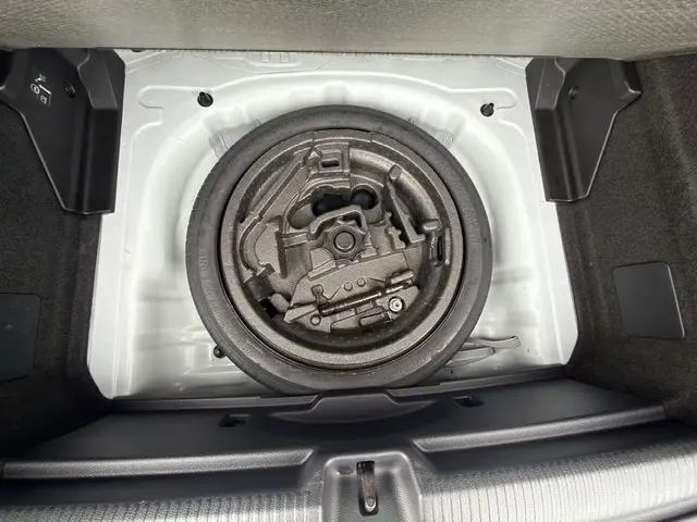 Vue plongeante sur la roue de secours et son rangement dans le coffre blanc de l'Audi Q2 30 TDI 116 Design 2021.