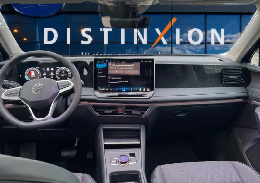 Vue intérieure avant du Volkswagen Tiguan 2025, tableau de bord noir avec écran tactile central et volant multifonction.