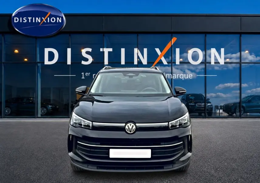 Vue avant d'un Volkswagen Tiguan noir 2025 garé devant une vitrine avec logo Distinxion.