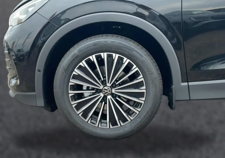 Gros plan sur la roue avant droite du Volkswagen Tiguan noir 2025 avec jante alliage multibranches distinctive.