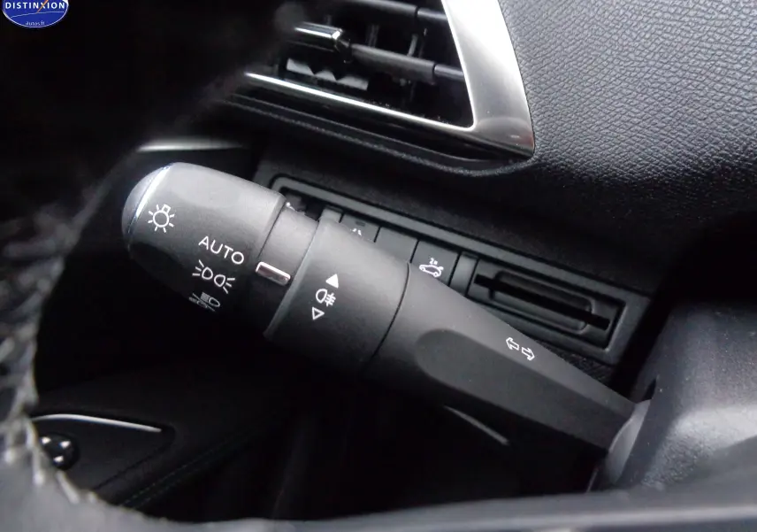 Gros plan sur la commande des feux et clignotants du Peugeot 3008 gris platinium, avec tableau de bord noir texturé.