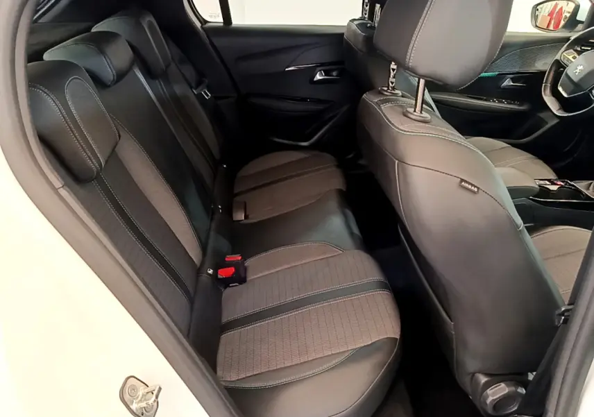Intérieur arrière de la Peugeot 208 blanc, vue côté gauche montrant les sièges en tissu et cuir avec surpiqûres contrastées.