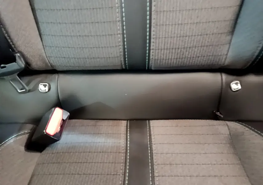 Gros plan sur la banquette arrière grise avec coutures contrastées et fixations Isofix visibles dans la Peugeot 208 blanche.