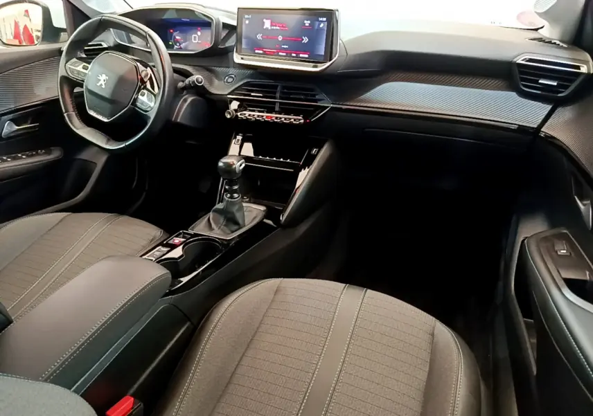 Intérieur avant de la Peugeot 208 PureTech blanc, vue côté conducteur avec tableau de bord et écran tactile central.