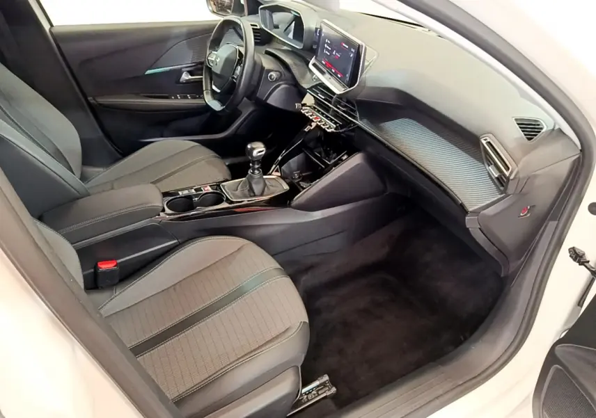 Intérieur de la Peugeot 208 blanc vue côté conducteur, tableau de bord moderne avec écran tactile et sièges gris.