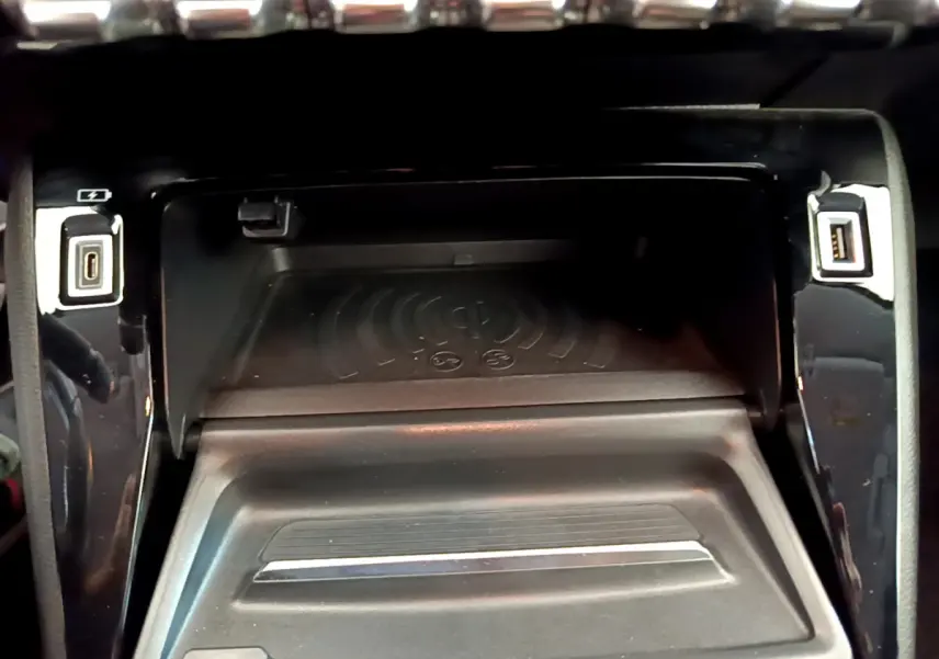 Zone de recharge par induction et ports USB intégrés dans la console centrale noire d'une Peugeot 208 blanche.