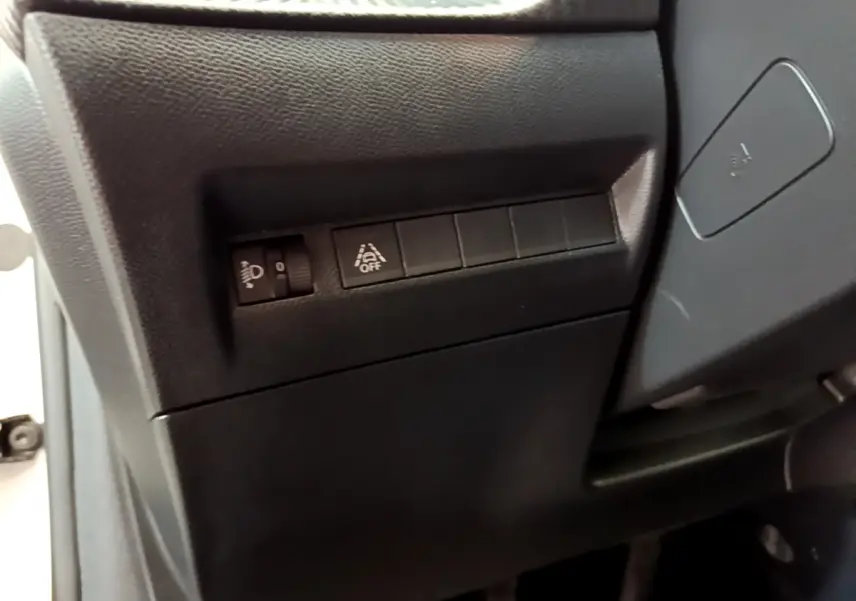 Détail des commandes de réglage des phares et d'activation de l'assistance au maintien de voie côté gauche sur Peugeot 208 blanc 2020.