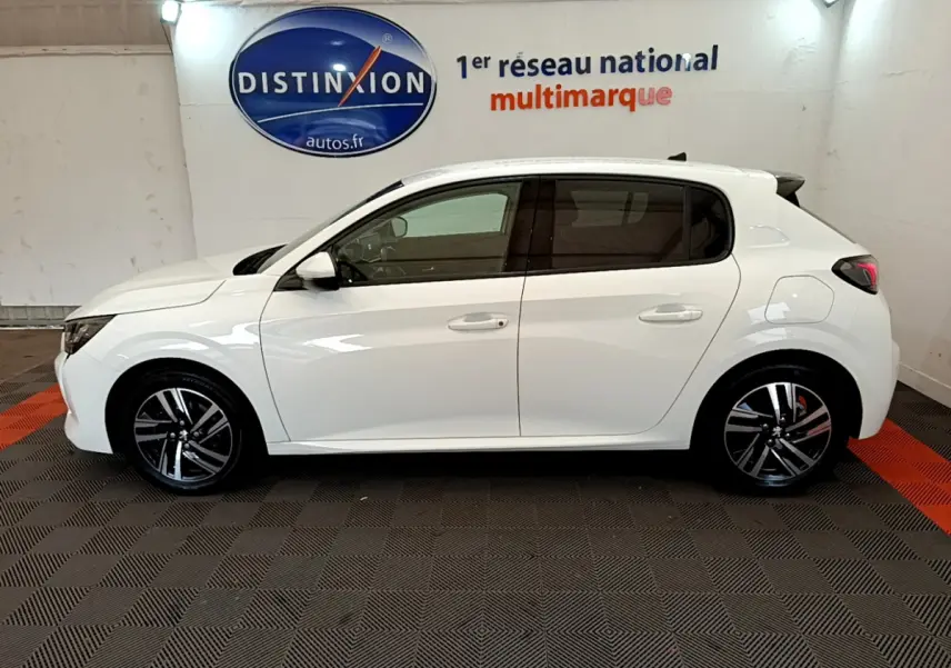 Profil côté gauche d'une Peugeot 208 blanche PureTech 100 S&S Allure Business de 2020 en intérieur showroom.