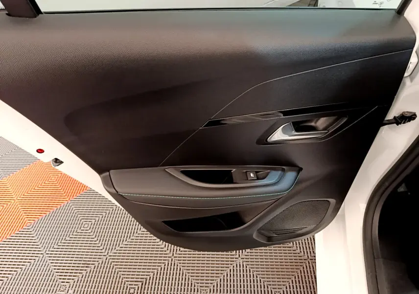 Gros plan sur la porte avant gauche noire de la Peugeot 208 blanche, avec poignée argentée et commande de vitre.