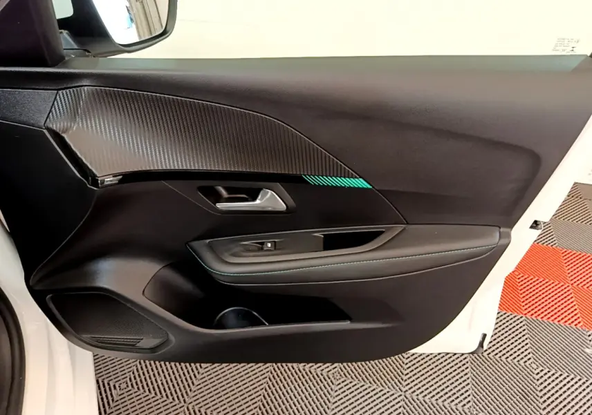 Vue intérieure de la porte côté gauche blanche d'une Peugeot 208 avec garniture noire et surpiqûres bleues.