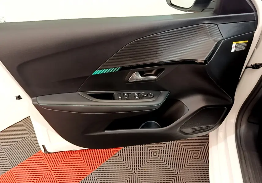 Vue rapprochée de la porte avant gauche blanche du Peugeot 208 2020, avec habillage noir et insert imitation carbone.