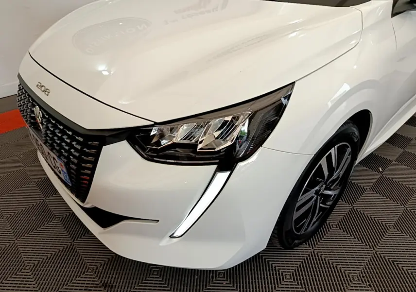 Vue 3/4 avant droit d'une Peugeot 208 blanche mettant en valeur ses phares LED et sa calandre distinctive.