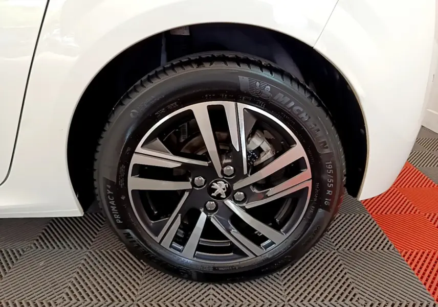 Gros plan sur la roue arrière droite de la Peugeot 208 blanche avec jante alliage noir et argentée.